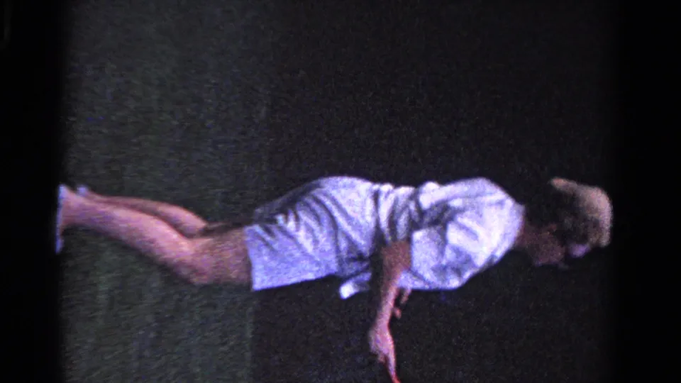 The woman bends low during tennis play on a grass court, with grain and color shifts from the 1958 8mm home-movie source.