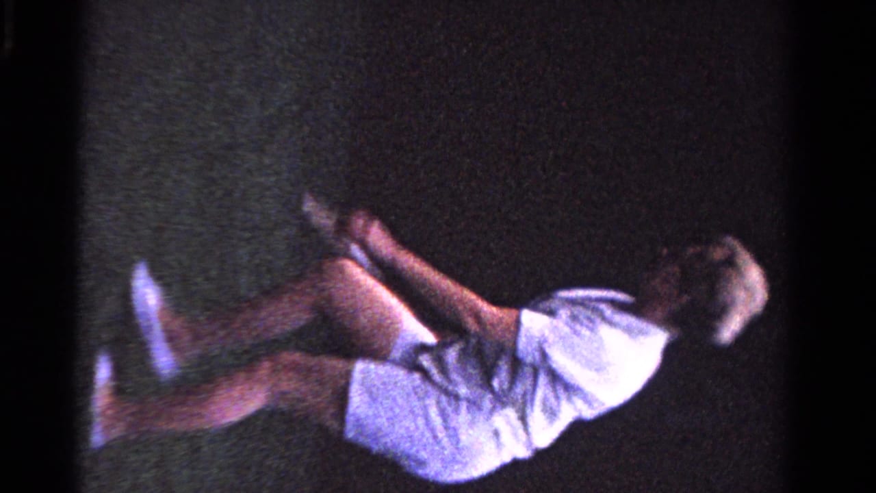 A woman in white tennis clothing moves quickly across a grass court in the 1958 Ontario family tennis scene.