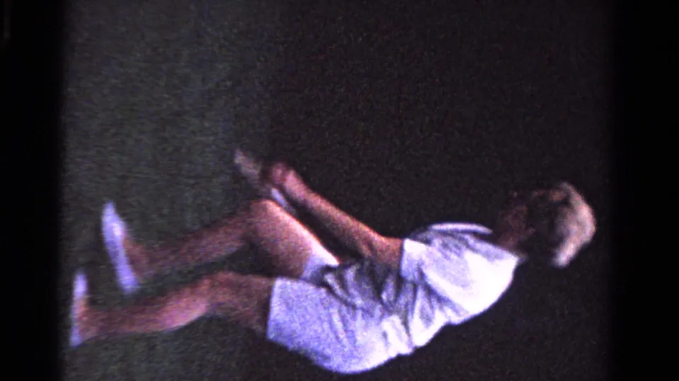 A woman in white tennis clothing moves quickly across a grass court in the 1958 Ontario family tennis scene.
