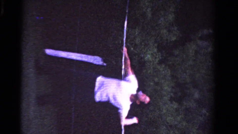 A young man reaches with his racket near a court line during nighttime tennis in 1958 Ontario home-movie footage.