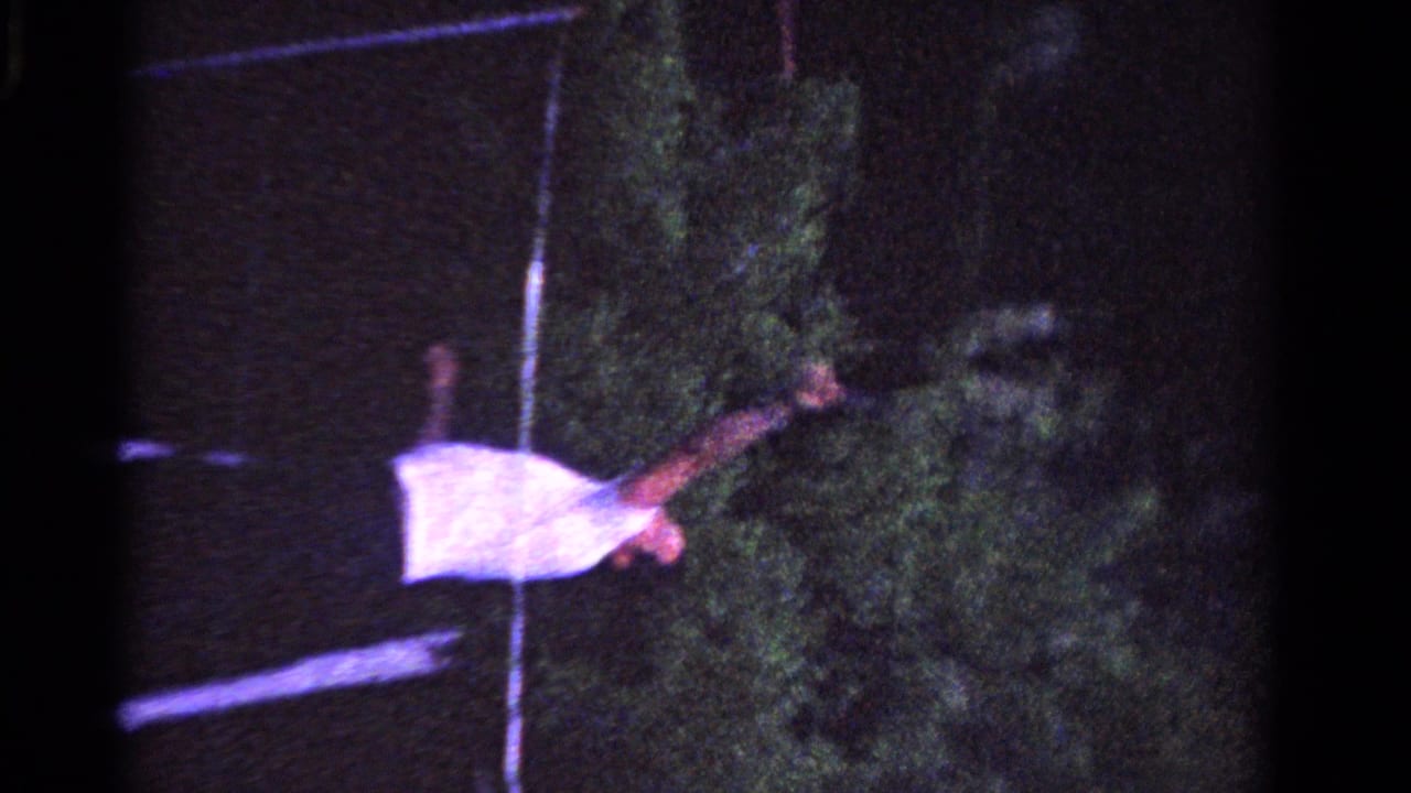 Woman in a light dress stands near a grass tennis court line at night.