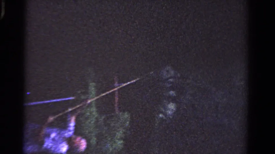 The man bends near the tree with the long pole angled upward, filmed in a dark, grainy 1958 Ontario home-movie frame.