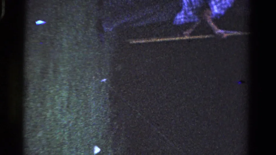 Underexposed 8mm frame with partial outdoor detail, film grain, and edge artifacts from the Ontario home-movie clip.