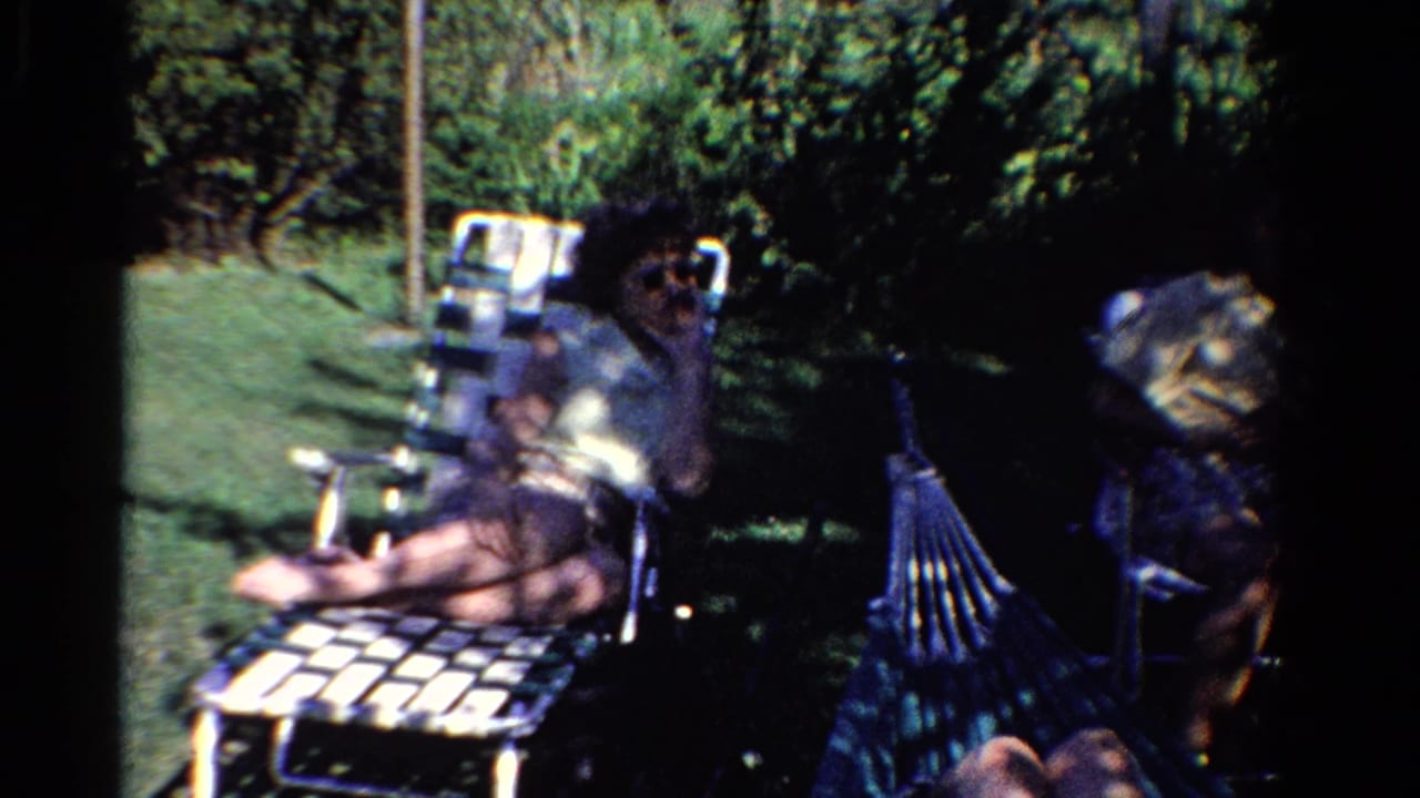 Two adults relaxing in a shaded backyard with lawn chairs and a hammock nearby.