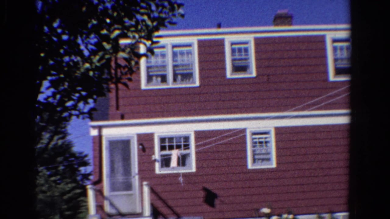 House exterior with screened door, white windows, clothesline, tree shade, and blue sky.