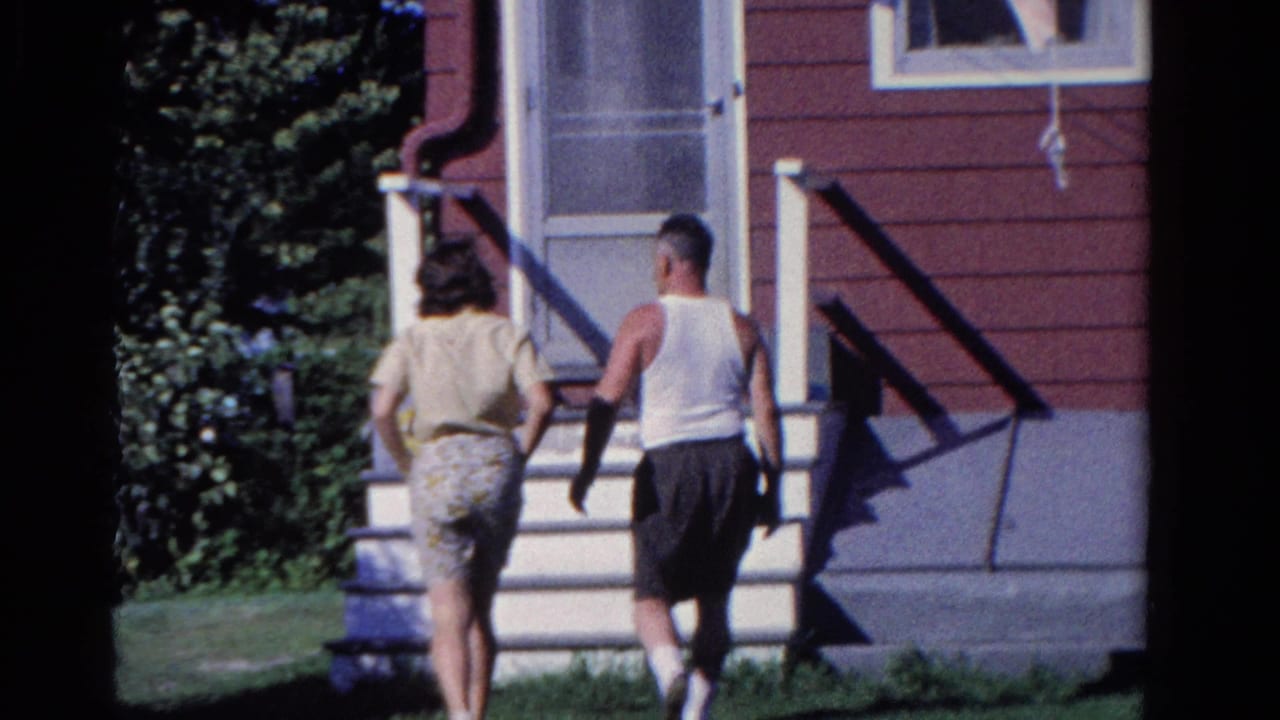 In 1958 Ontario home-movie footage, a woman and man approach the white steps of a red-sided house.