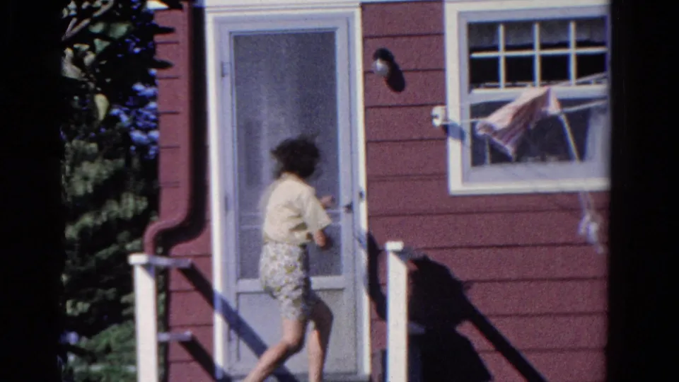 The woman turns toward the screen door of the red-sided Ontario house, while laundry hangs in the nearby white-trimmed window.