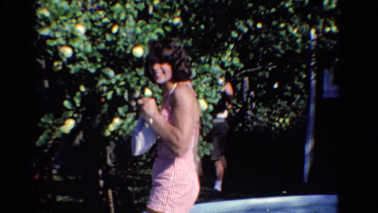 Young woman in a pink striped outfit smiles beside a fruit tree.