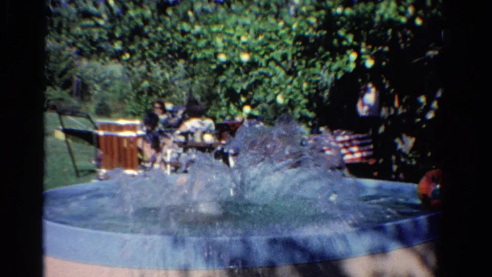1958 Ontario backyard pool scene with a large splash, shaded trees, and seated people beyond the water.
