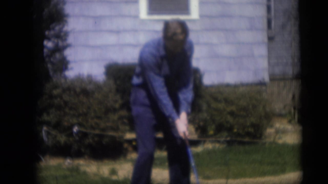 In Camden, New Jersey home-movie footage from 1959, an adult man stands in a suburban yard preparing to swing a golf club.