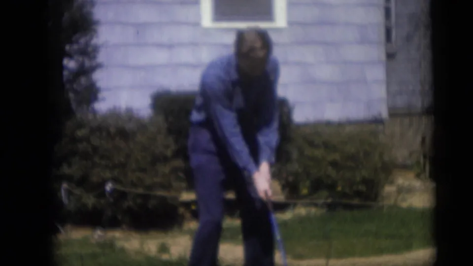 In Camden, New Jersey home-movie footage from 1959, an adult man stands in a suburban yard preparing to swing a golf club.