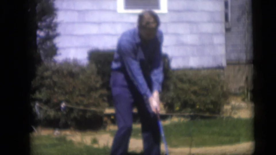 A 1959 home-movie frame shows the man still addressing the ball in a Camden yard, with soft focus and visible 8mm film borders.