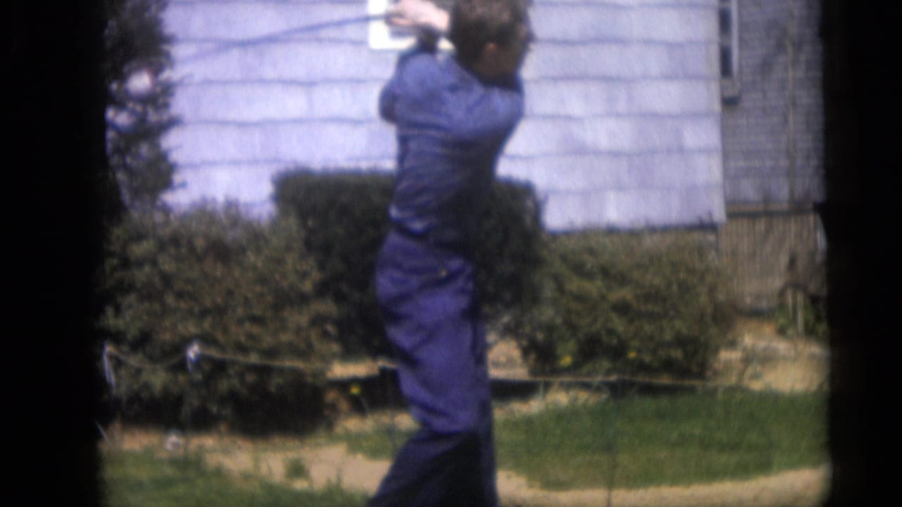 In the 1959 backyard scene, the man is seen from the side as his golf swing continues before shrubs and house siding.