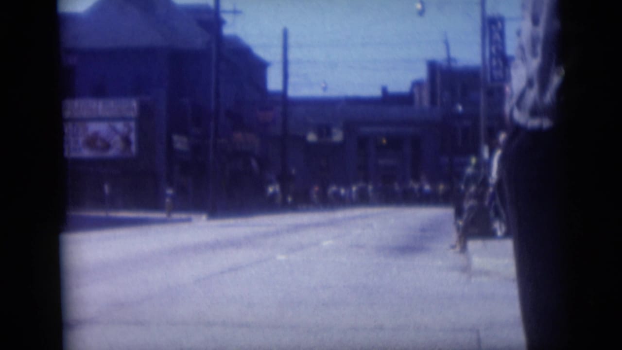 1959 Camden street view showing a wide avenue, distant buildings, signs, and a partially visible foreground pedestrian.