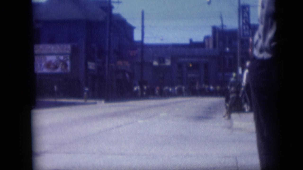 Wide avenue and storefronts with a cropped person standing near the right edge.