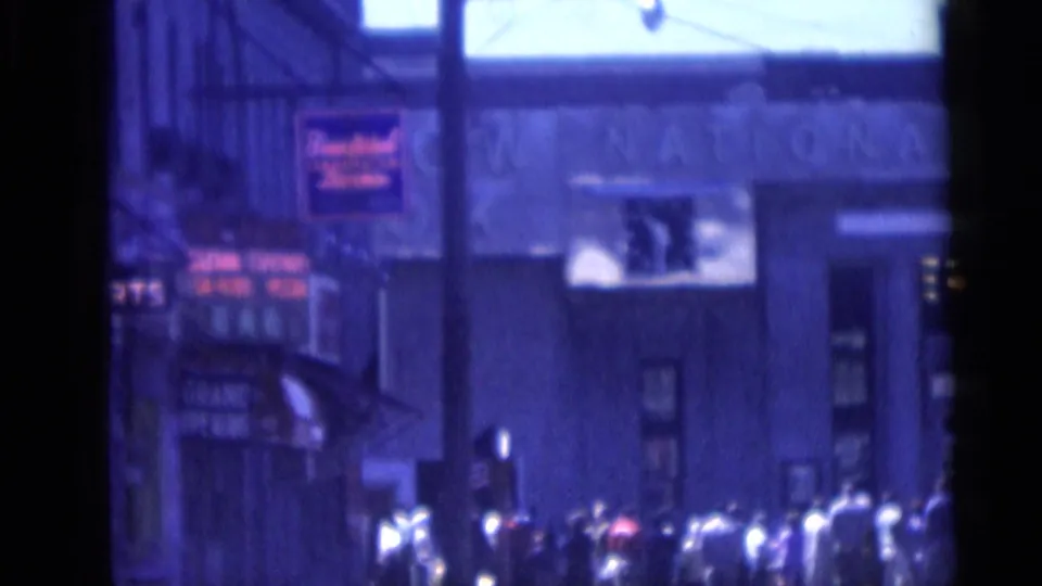 1959 Camden sidewalk crowd below commercial signs and building facades, filmed with soft blue 8mm color.