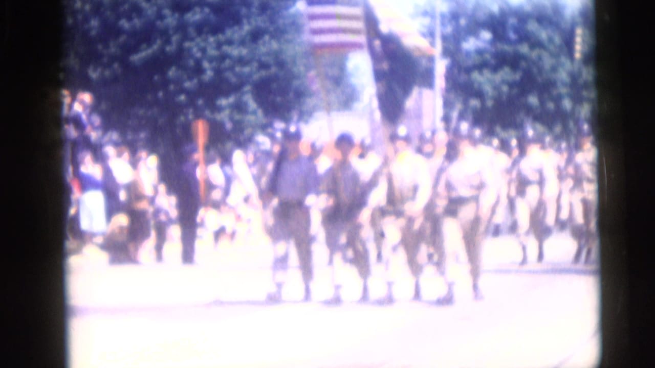 Uniformed soldiers march in a Camden, New Jersey patriotic parade in 1959, with spectators lining the shaded street.