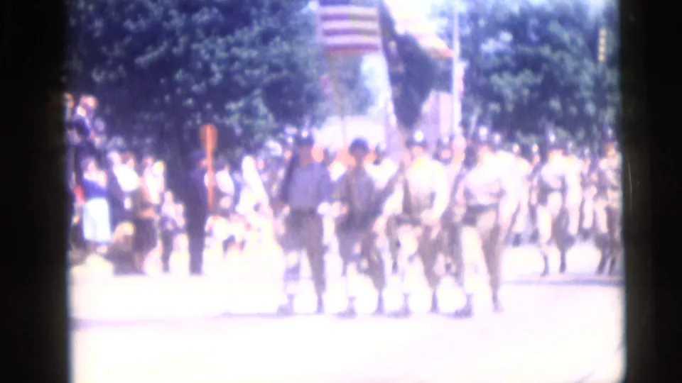 Uniformed soldiers march in a Camden, New Jersey patriotic parade in 1959, with spectators lining the shaded street.