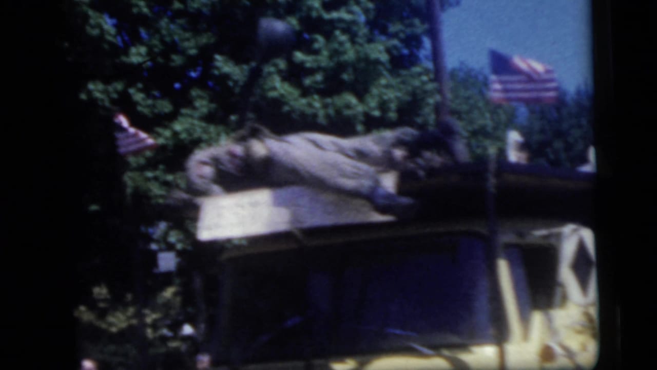Decorated yellow truck roof with flags and a figure lying or posed on top.