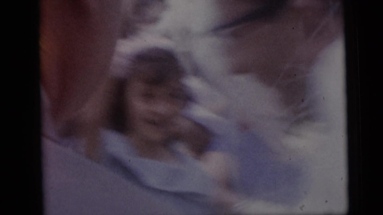 Soft, blurred close view of a person in pale wedding clothing near other figures.