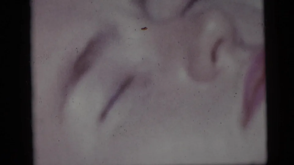 Soft 1959 Camden beach frame showing the resting girl’s face in close-up, with faded color and dust from the 8mm scan.