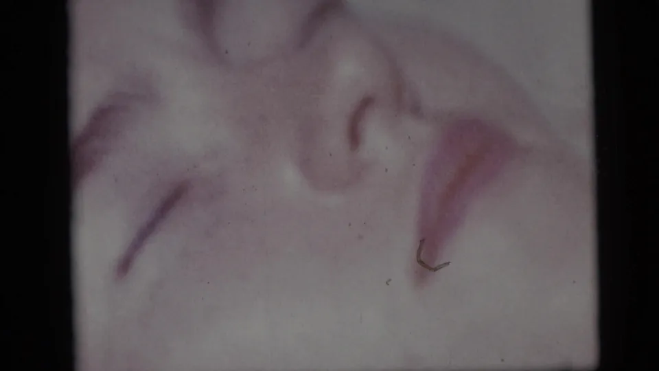 1959 8mm home-movie frame from Camden, New Jersey, with the sleeping girl’s face and hair filling the beach close-up.