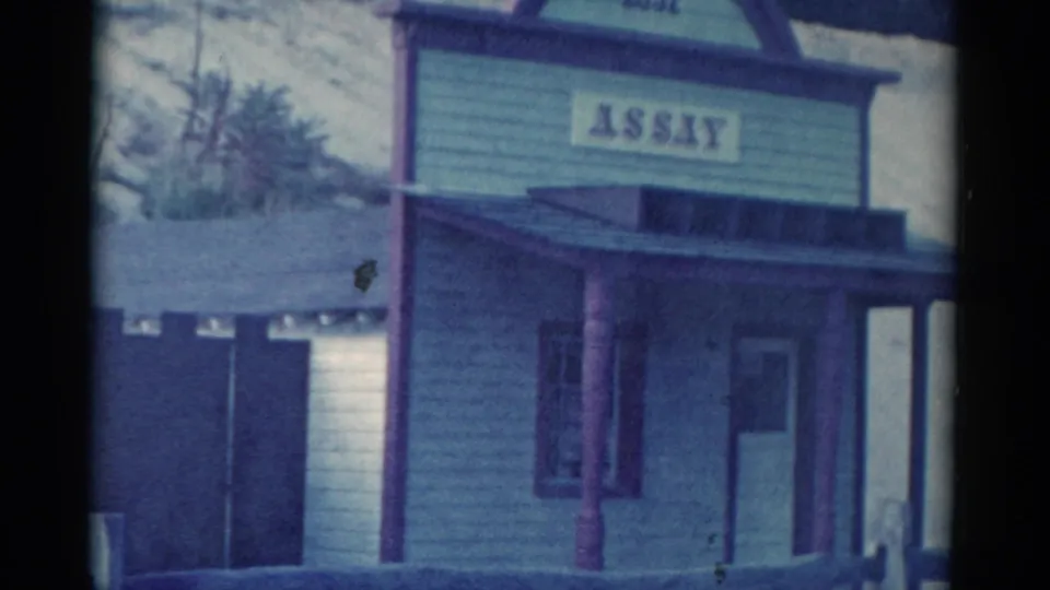 1959 Catskill-area frame showing a Western-style storefront with porch roof, posts, doorway, and an ASSAY sign.