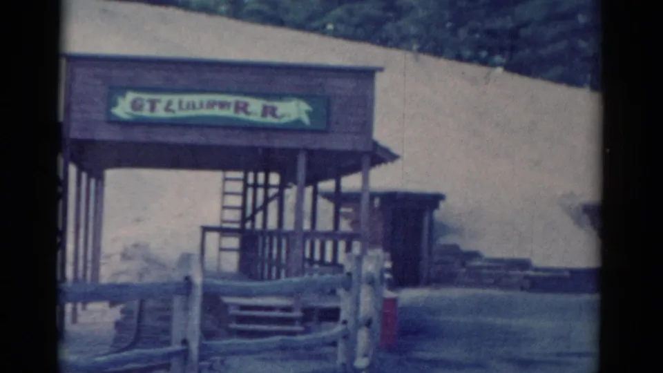 Catskill, New York 1959 home-movie frame of the GT Lilliput R.R. entrance, with rail fence, steps, porch posts, and a small side structure.