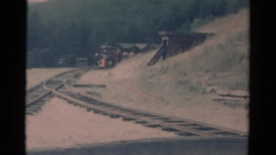 1959 Catskill-area 8mm frame showing the red train nearer to the curve, with several rails crossing the foreground.