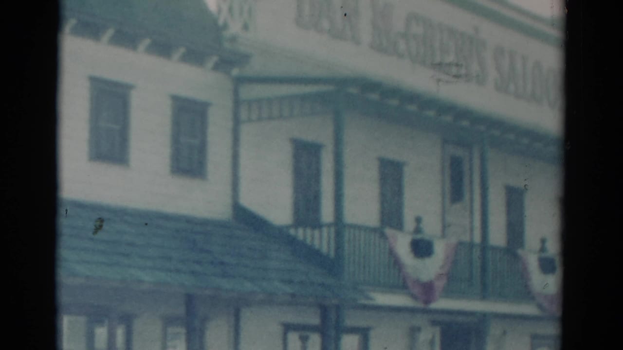 1959 Catskill, New York home-movie frame showing a two-story wooden saloon exterior with balcony rail and patriotic bunting.
