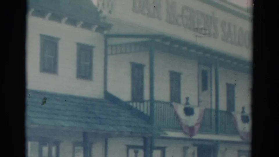 1959 Catskill, New York home-movie frame showing a two-story wooden saloon exterior with balcony rail and patriotic bunting.