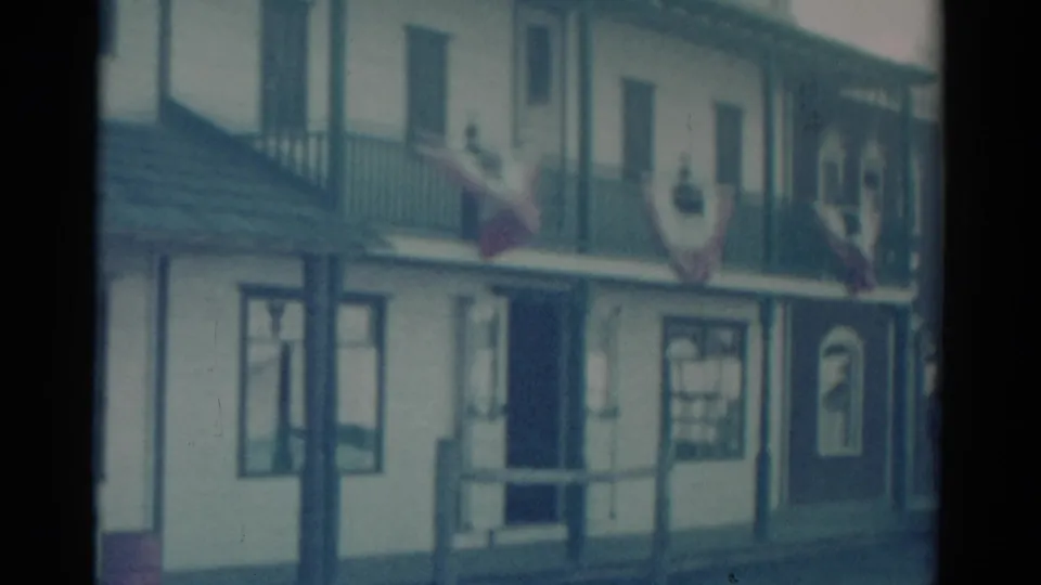 1959 Catskill home-movie view of the saloon exterior, showing the street-level doorway, windows, balcony, and draped bunting.