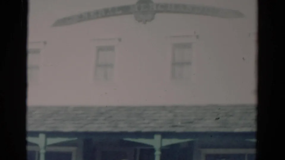Faded 1959 Catskill, New York store facade with porch roof, upper windows, and partial sign lettering above the frame center.
