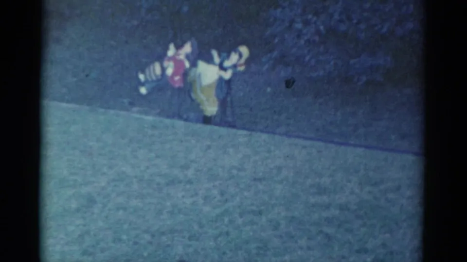 The 1959 Catskill home-movie frame shows the costumed pair farther along the grass path, still viewed from a distance.