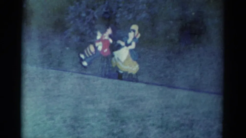 Two costumed performers in the Catskill 1959 footage pass near the camera's center, with striped pants and a yellow skirt visible.