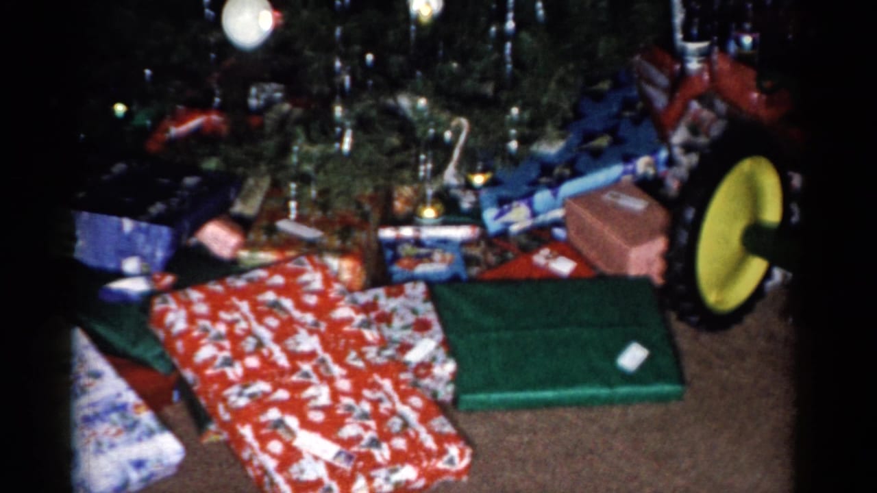 Wrapped Christmas presents and a toy tractor beneath a decorated tree.