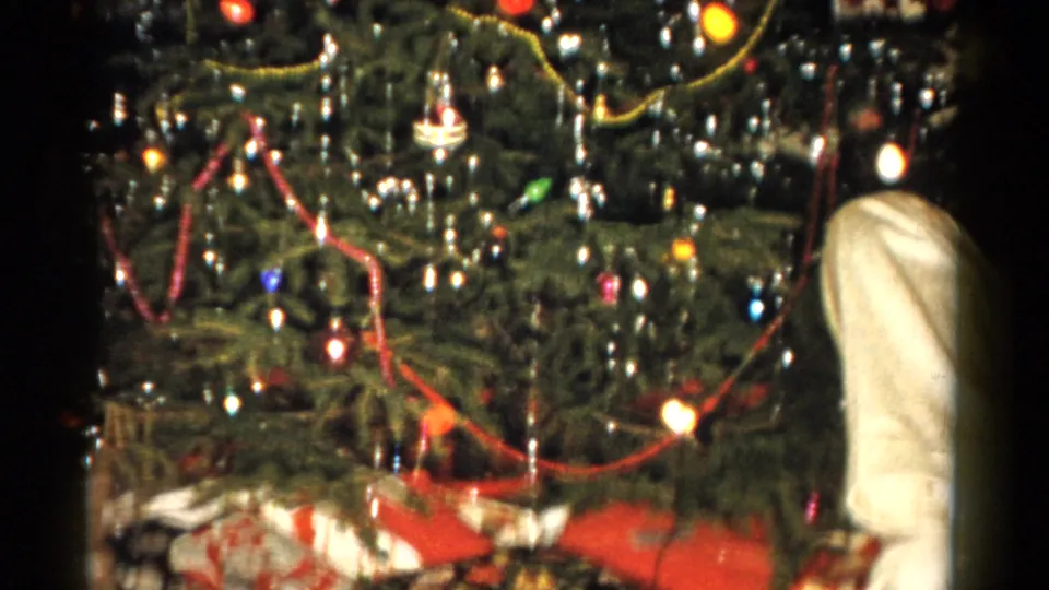 1959 Catskill interior with a decorated Christmas tree, gifts, and a partially visible person standing near the right edge.