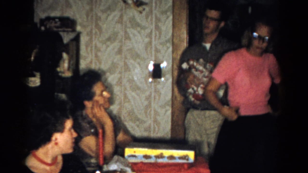 Standing adults appear near a doorway while seated women remain at the gift table.