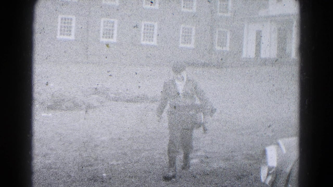 1959 Hagerstown home-movie frame showing a man walking across a yard toward the camera, with residential buildings behind him.