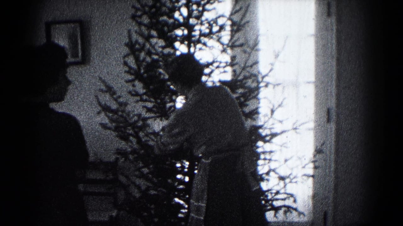 In a 1959 Hagerstown home-movie frame, silhouetted family figures stand by a Christmas tree against a bright window.