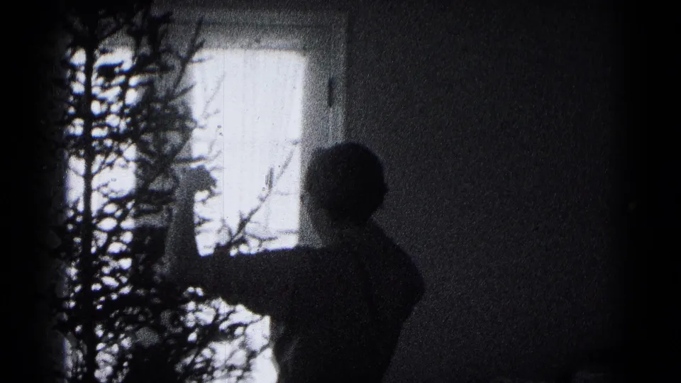 A silhouetted family member appears to adjust the Christmas tree in a dark 1959 Hagerstown interior.