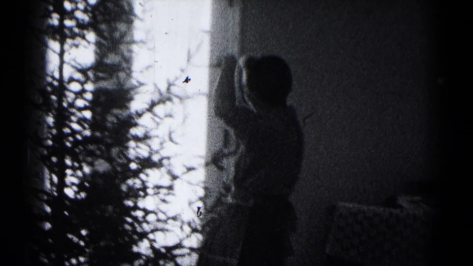 A backlit family member raises both arms near the Christmas tree in this 1959 Hagerstown home-movie frame.