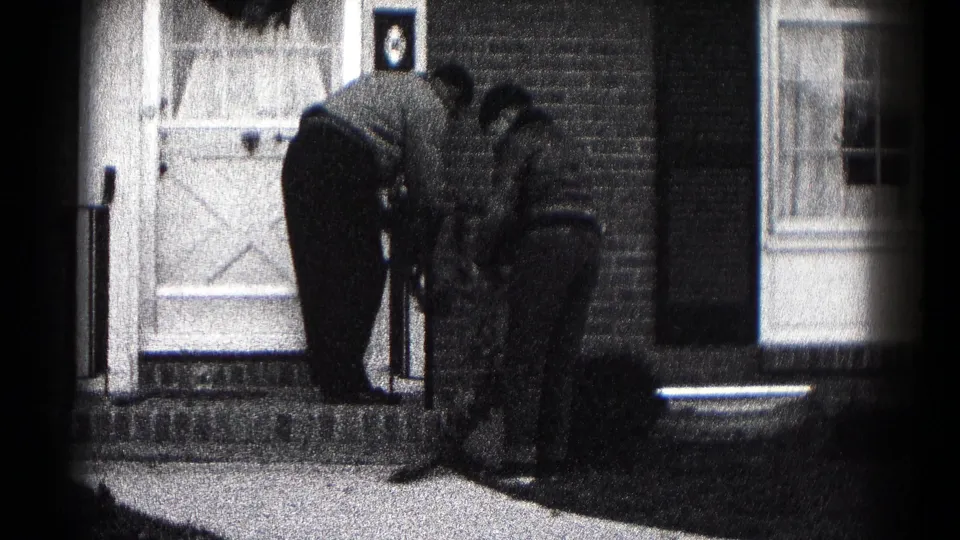 Two adults bend together outside a brick residence in Hagerstown, Maryland, near the white front door and porch steps.