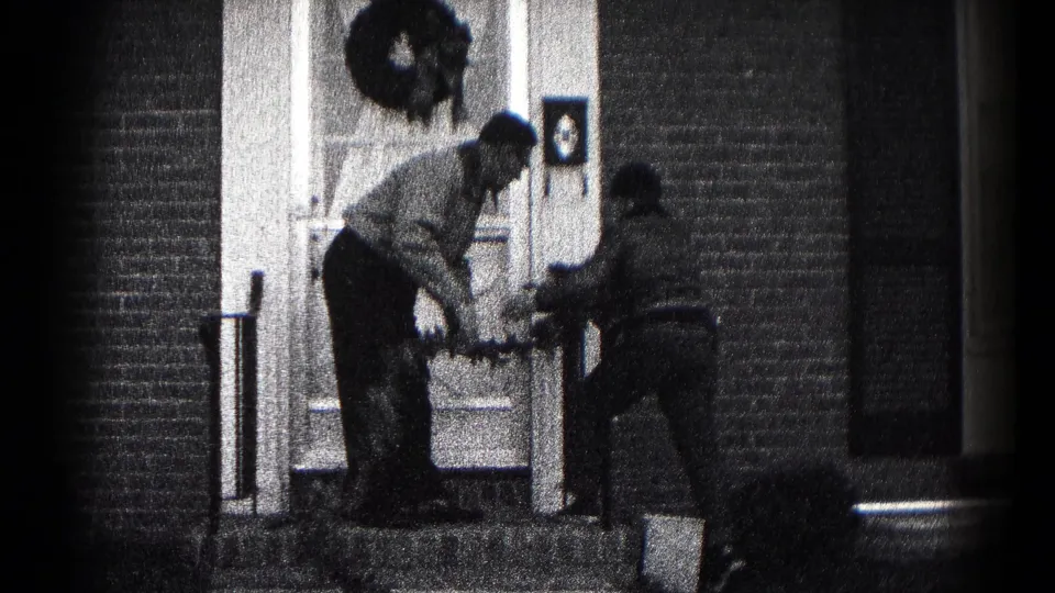 In 1959 Hagerstown home-movie footage, a father and son appear to handle a wreath at a brick home's front entrance.