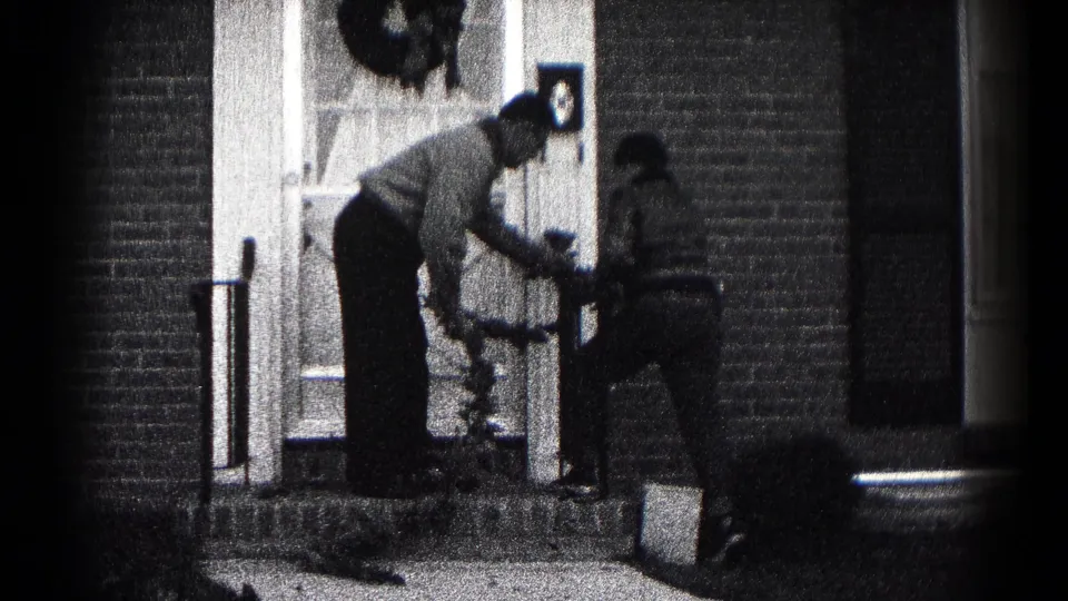 The father leans in to guide the younger person with the wreath at the brick home's entry in Hagerstown, Maryland.