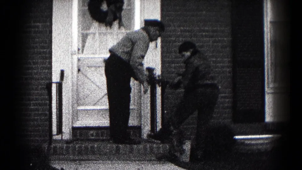 At the end of the brief clip, the father and son remain by the steps with the wreath near the brick home's doorway.