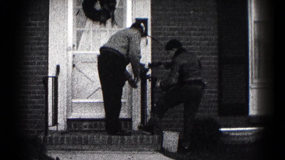 In 1959 Hagerstown home-movie footage, two men adjust Christmas decorations at the front door of a brick residence.