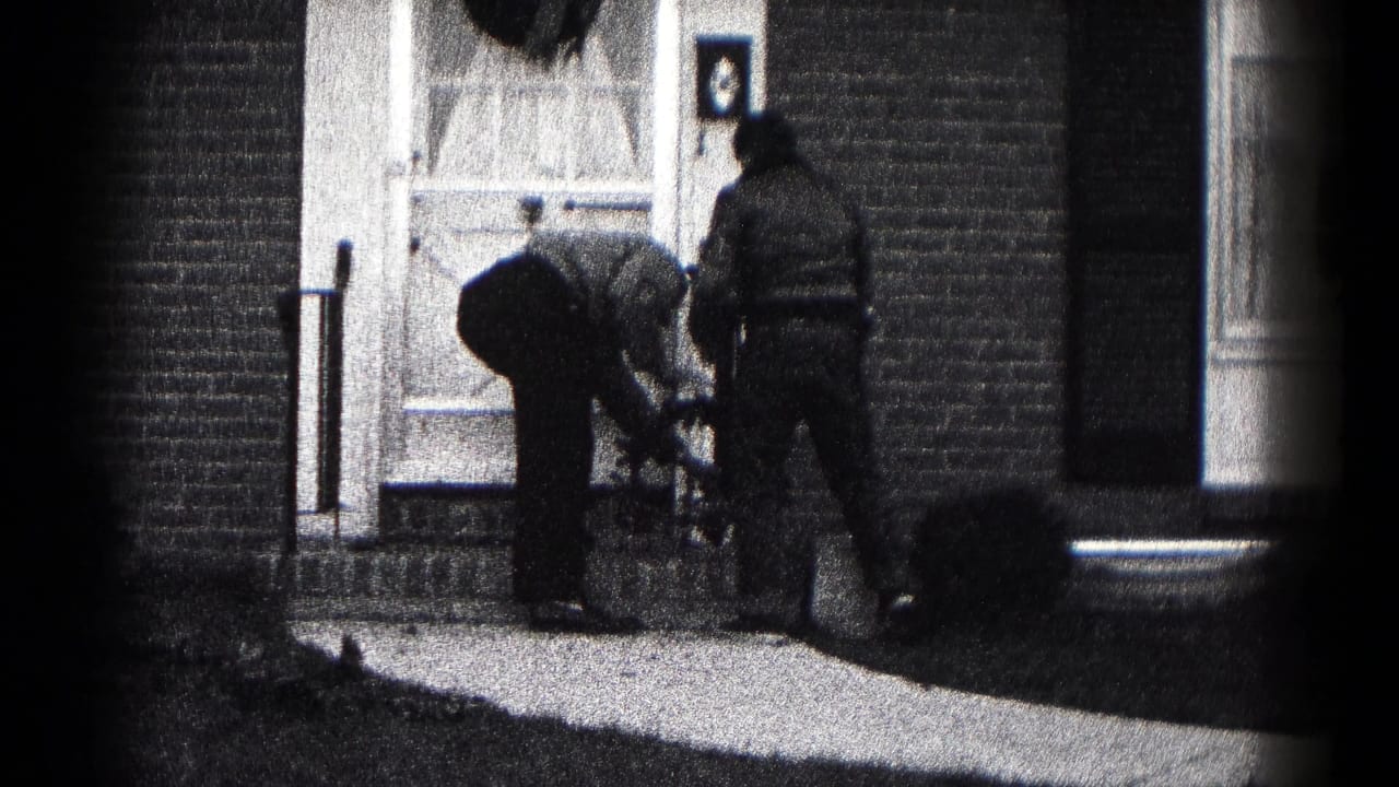 Two men continue working at a decorated front doorway in Hagerstown, Maryland, with one bending near the steps.