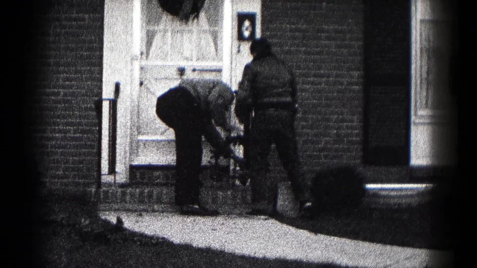 Two men continue working at a decorated front doorway in Hagerstown, Maryland, with one bending near the steps.