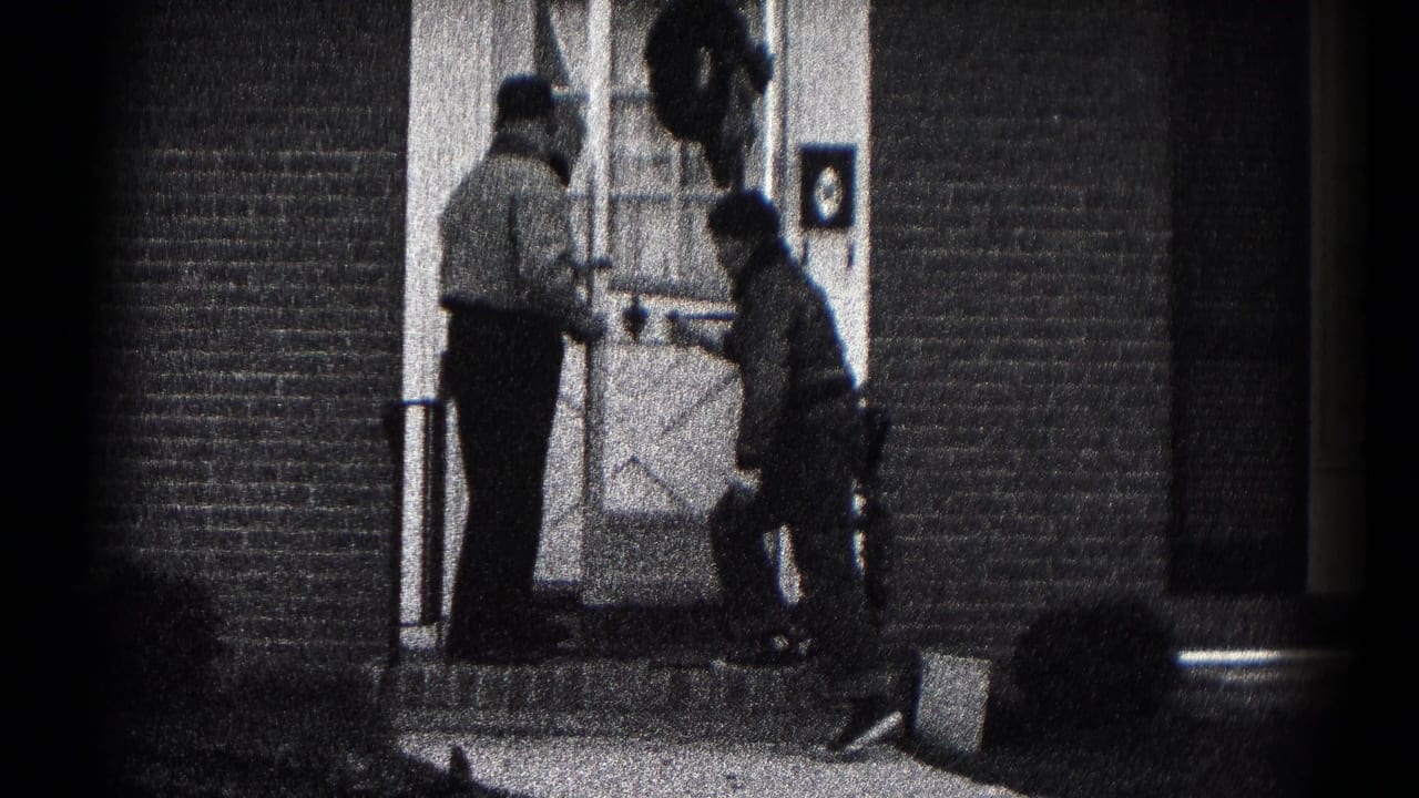 Two men in jackets appear to adjust a plant or pot at a brick front entrance in Hagerstown, Maryland, 1959.